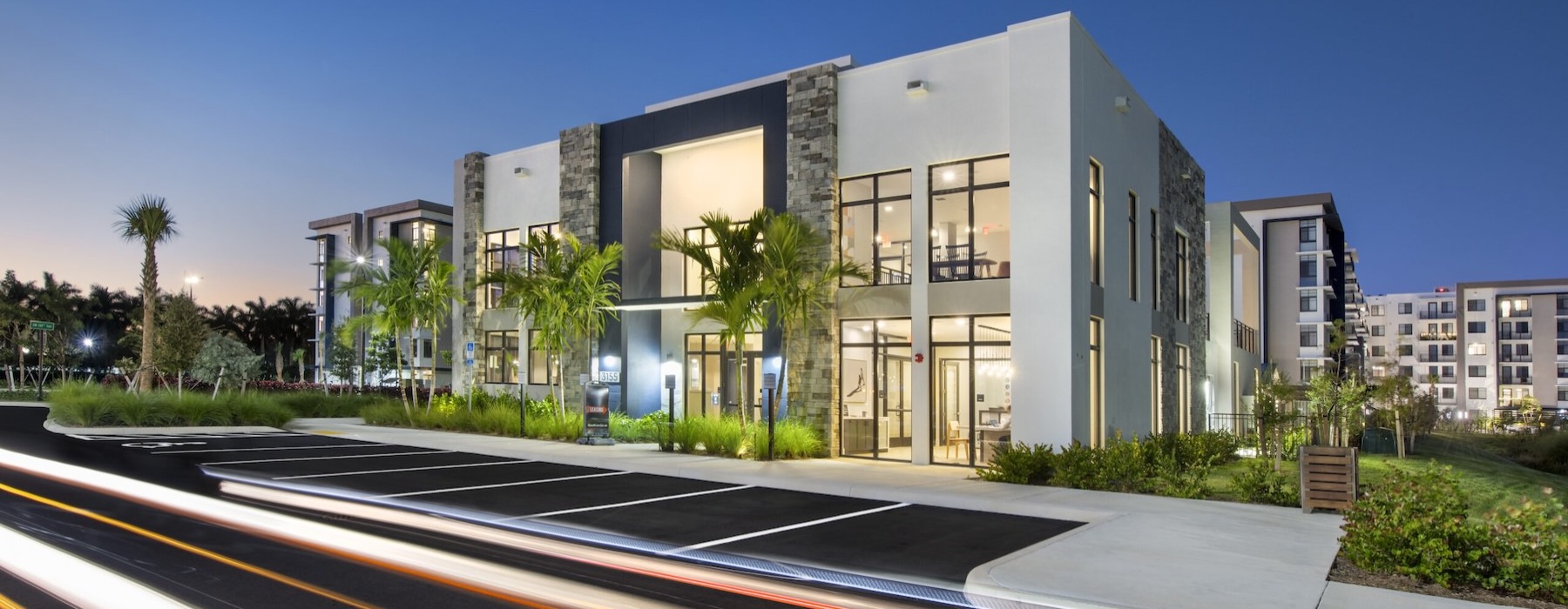 exterior of a building with large windows and palm trees around it